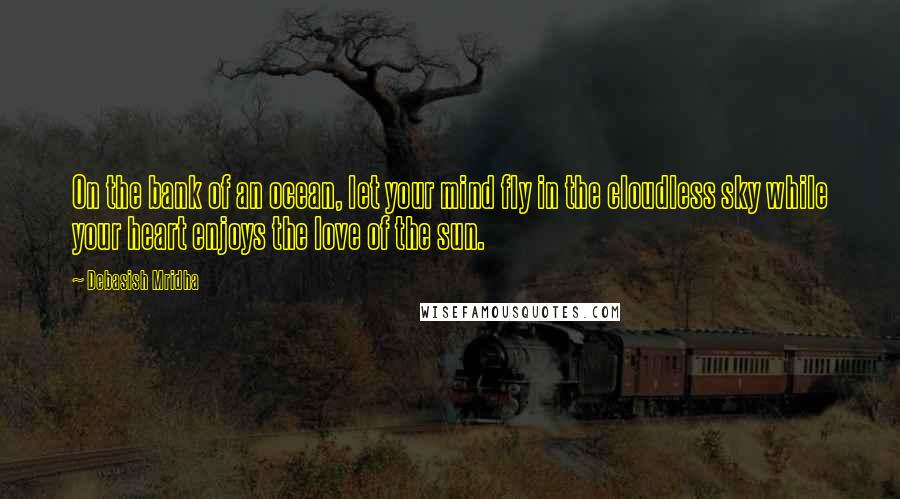 Debasish Mridha Quotes: On the bank of an ocean, let your mind fly in the cloudless sky while your heart enjoys the love of the sun.