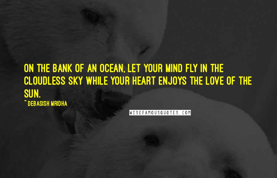 Debasish Mridha Quotes: On the bank of an ocean, let your mind fly in the cloudless sky while your heart enjoys the love of the sun.